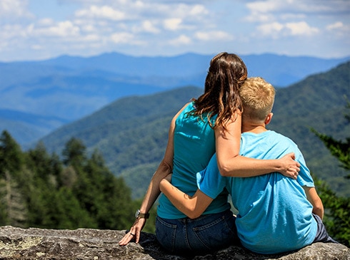 Mother and son embraced, seated on Newfound Gap Overlook wall looking towards the Smoky Mountains
