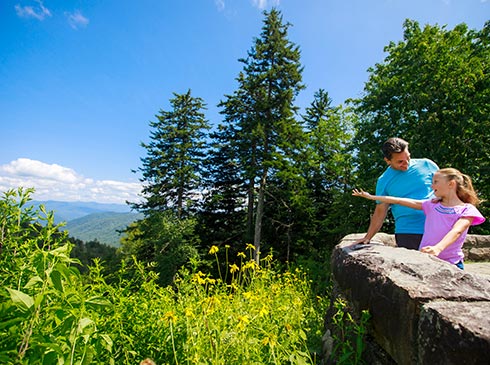 Father and daughter standing at Newfound Gap Overlook, looking out at Smoky Mountains scenery