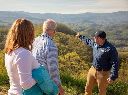 Pink® Jeep® tour guide pointing out the Smoky Mountains range to couple on Foothills Parkway Smoky Mountains tour.