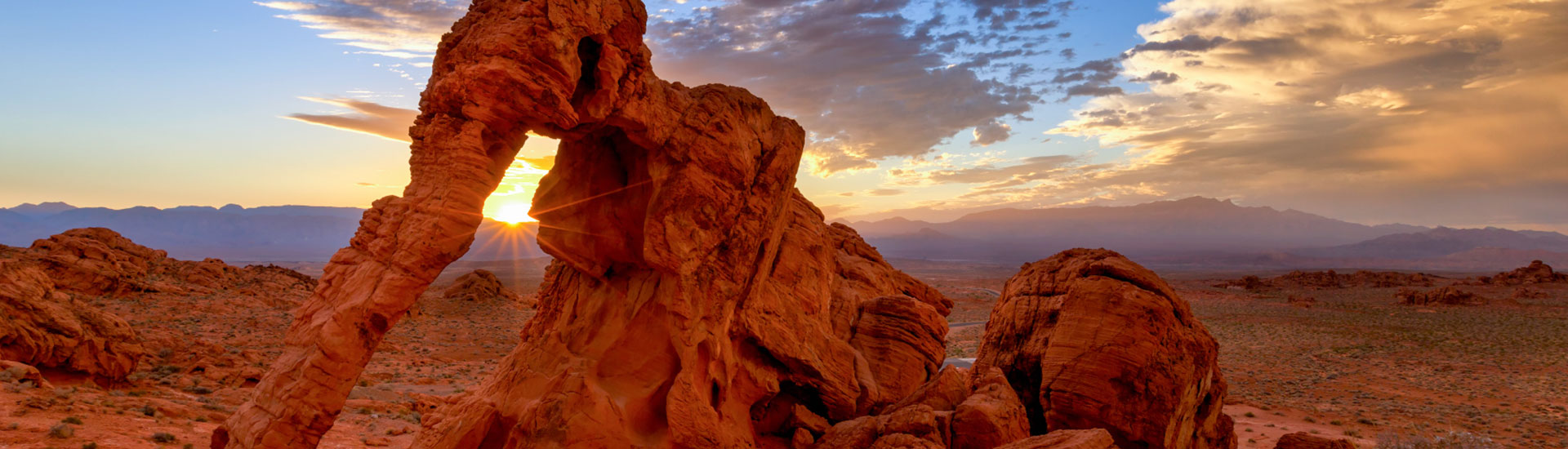 Golden sun setting against a violet blue sky behind Elephant Rock at Valley of Fire State Park, Nevada.