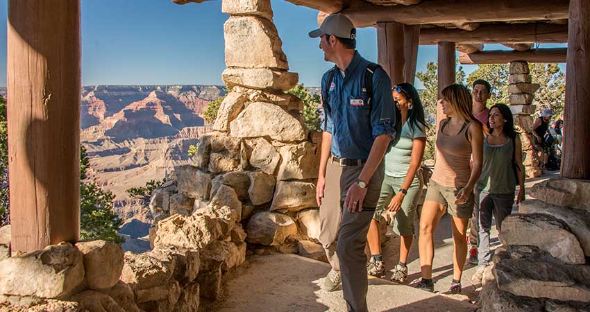 Pink Jeep® Adventure guide leading tour guests along the walkway at Hermits Rest, overlooking the Grand Canyon.
