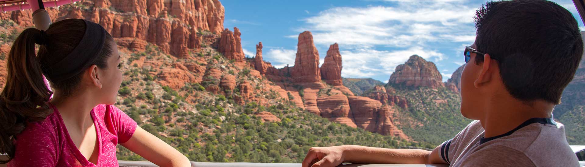 Teenage boy and girl looking out towards the red rock formations surrounding the Chapel of the Holy Cross, Scenic Sedona Tour, Arizona.