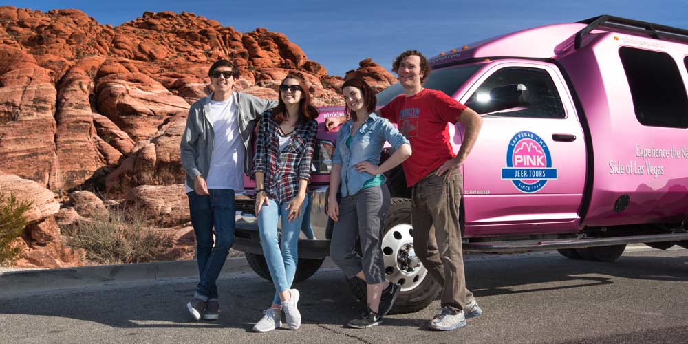 Family of four posing in front of Pink Adventure Tour Trekker at Red Rock Canyon, Nevada.