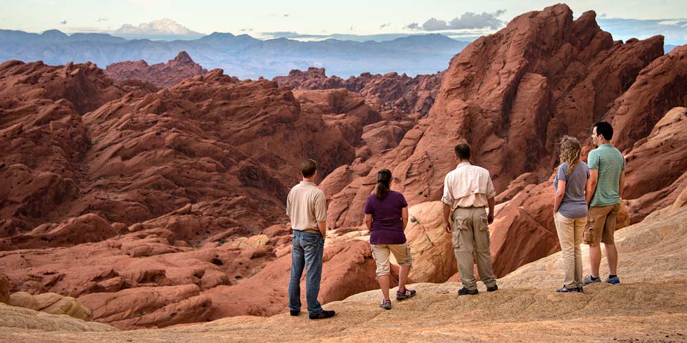 Pink Jeep adventure guide and tour guests viewing red rock formations at Valley of Fire State Park, NV.