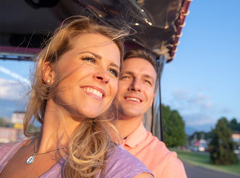 Close-up of couple looking out and upward from a Pink Jeep Wrangler, while riding through Pigeon Forge, TN.