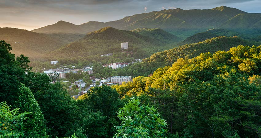 Scenic aerial view of the green Smoky Mountains foothills surrounding Gatlinburg, TN during sunrise.