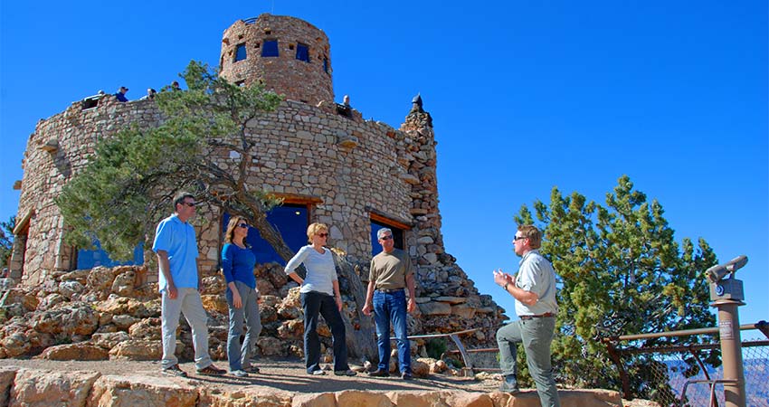 Pink Jeep Tours Grand Canyon guide and guests talking on the terrace in front of the Desert View Watchtower, Grand Canyon South Rim.