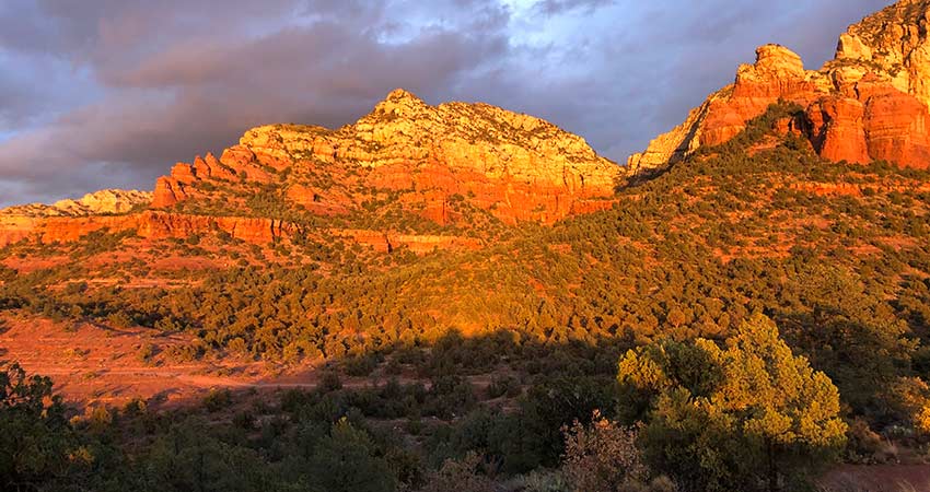 Sedona's famous red rock formations glowing in the evening sun with a purple cast sky above during Pink Jeep's Broken Arrow Twilight tour.