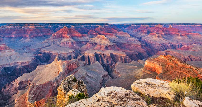 A pink glow descends over the geological formations of the Grand Canyon's South Rim during a late afternoon sky, Grand Canyon National Park.