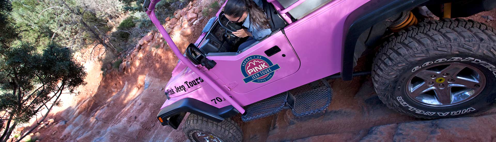 Pink Jeep Adventure Guide looking down the driver's side of a Jeep Wrangler while navigating the steep Road-of-No-Return on the Broken Arrow Tour.