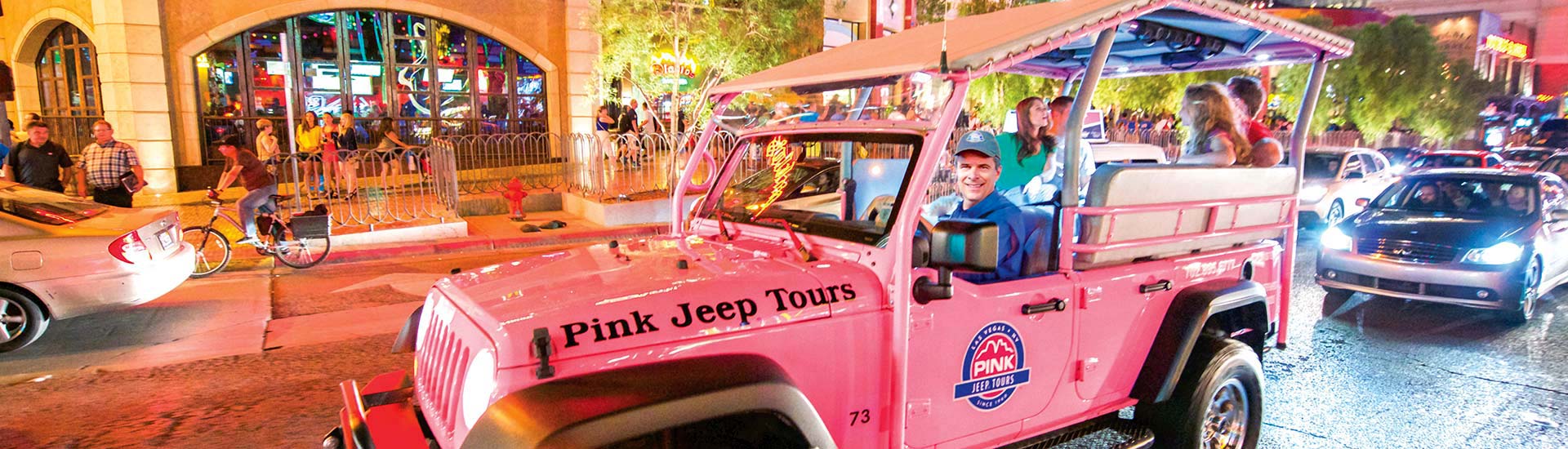 Pink Jeep Tours Las Vegas tour guide drives a Jeep Wrangler down the Las Vegas Strip under the neon lights on the city's Bright Lights Tour. 