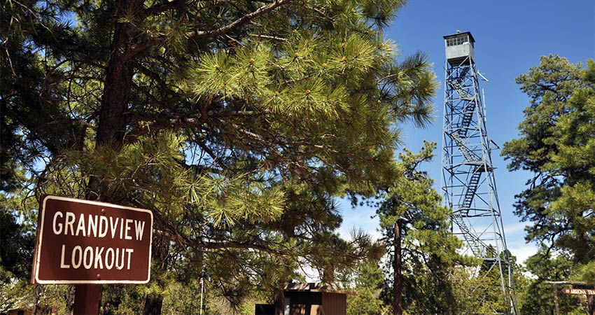 Grandview Lookout sign with ponderosa pine trees and original steel fire lookout tower in the background, Kaibab National Forest, Arizona.