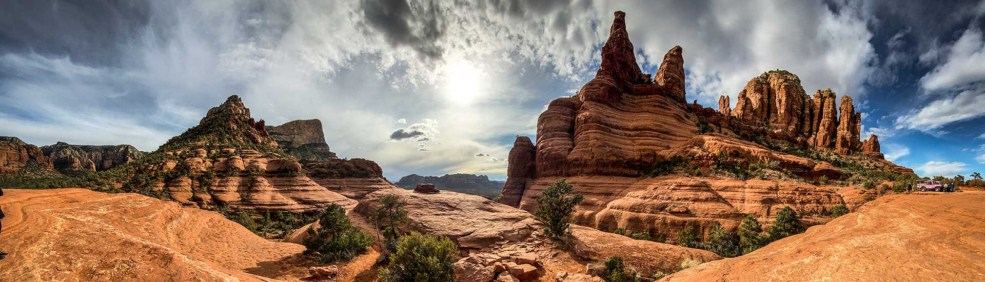 Dramatic view of Sedona's Chicken Point rock formation with the sun glowing through late afternoon clouds, Pink Jeep Broken Arrow Twilight tour.