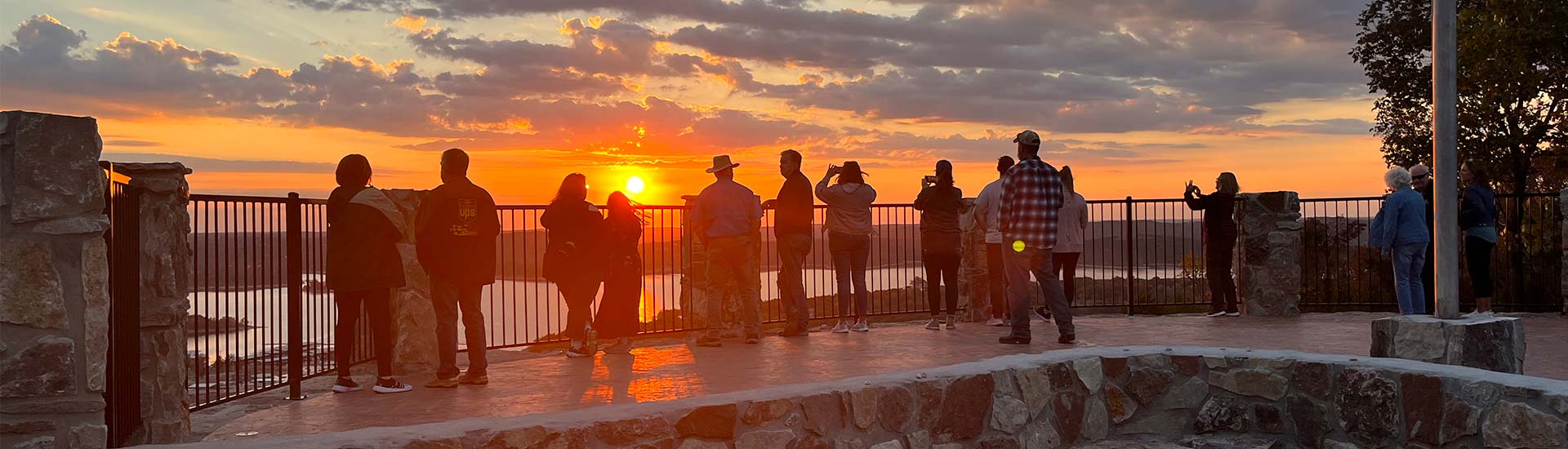 Pink Jeep tour guests watching a beautiful golden sunset over Table Rock Lake from atop Baird Mountain, the Best of Branson Sunset Tour.