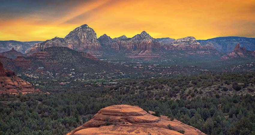 Panorama view of Sedona from the tip of Submarine Rock lit by a deep golden sunset during Pink Jeep's Broken Arrow Twilight Tour.