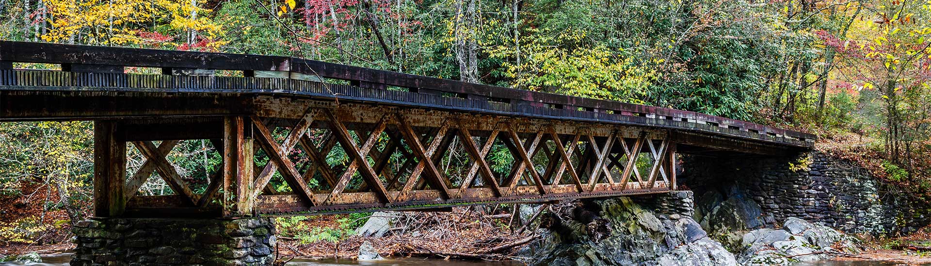 An antique, steel bridge surrounded by fall foliage crosses the Little River in Elkmont, near Great Smoky Mountains National Park.