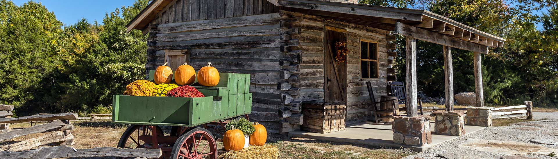 Log cabin and pumpkin wagon sits atop Baird Mountain surrounded by early fall foliage, Pink Jeep Tours Best of Branson tour.