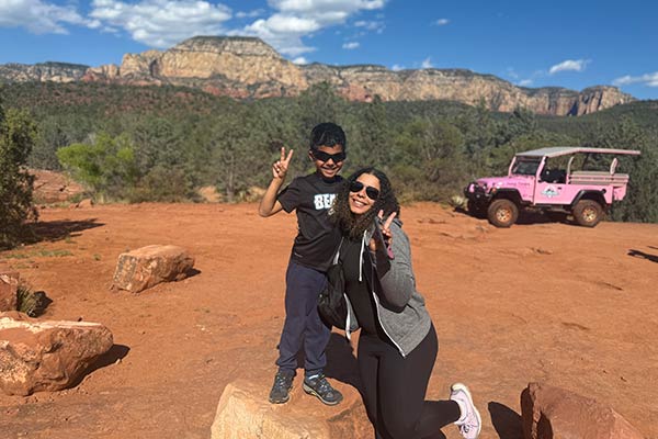 Mother and young boy posing for the camera, making a peace sign, with a Pink Jeep Wrangler and Sedona red rock landscape in the background.