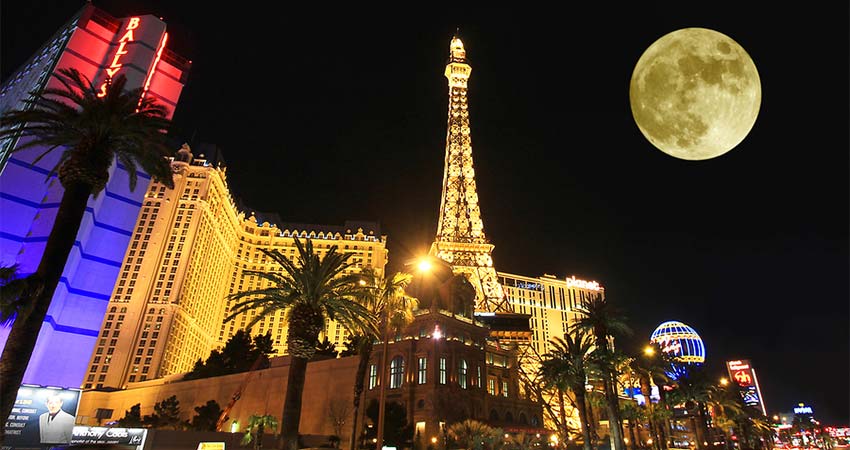 A brilliant moon-lit nighttime view of the Las Vegas neon skyline looking up at the Eiffel Tower Paris Hotel along the Las Vegas Strip.