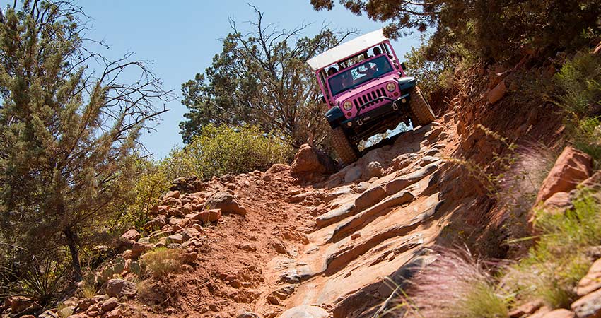 Closeup of a Pink Jeep Wrangler descending the steep Road-of-No-Return stone staircase, on Sedona's exclusive Broken Arrow tour.