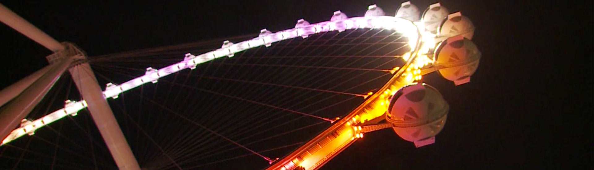 Close-up of the observation pods on the Las Vega High Roller glowing with neon lights as the wheel swirls through the sky.