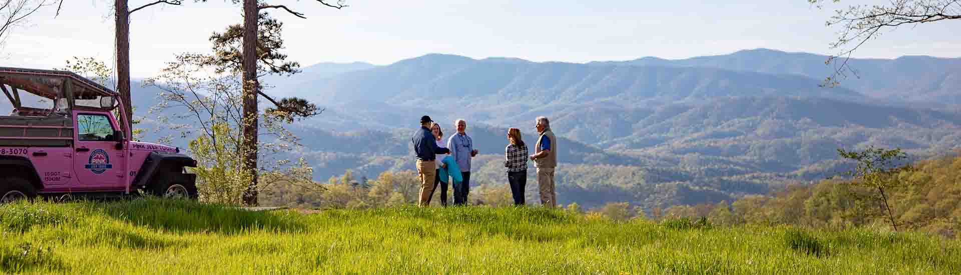 Expansive view of Smoky Mountains with Pink Jeep Foothills Parkway tour guests and jeep in foreground