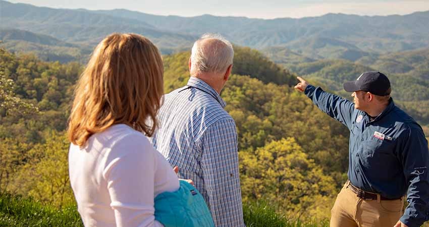 Pink® Jeep® tour guide pointing out the Smoky Mountain ridgelines to a couple on Foothills Parkway Smoky Mountains tour.